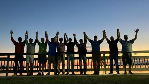 A row of men with hands clasped at sunest